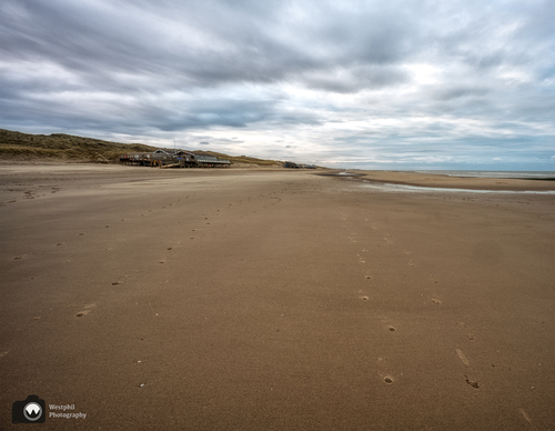Strand met in de verte een paviljoen