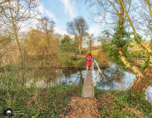 Laura in rode jas van achter gezien op een bruggetje 
