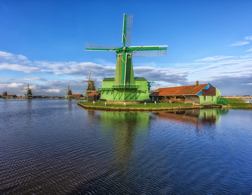 Fel groene molen met in de achtergrond meer molens