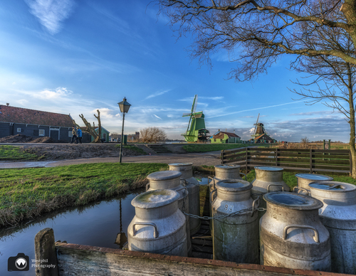 Groep melkbussen met op de achtergrond de Zaanse schans molens