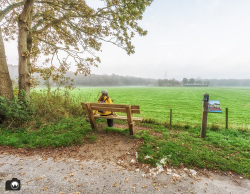 Laura op een bankje aan de velden