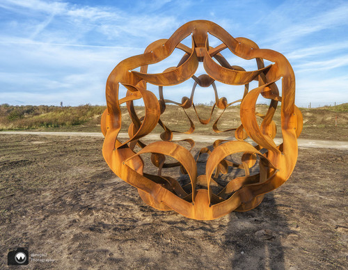 laura op de rug gezien met open armen in een duinpan