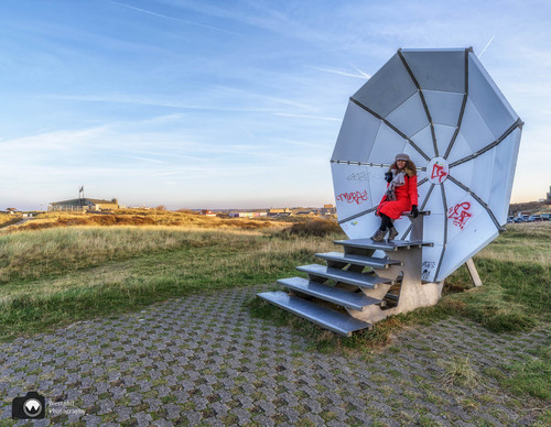 laura op de rug gezien met open armen in een duinpan