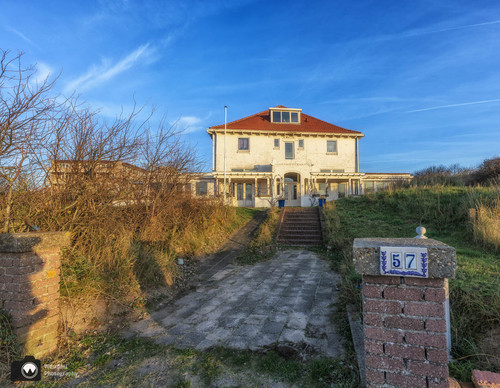 laura op de rug gezien met open armen in een duinpan