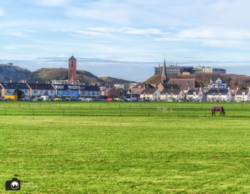 laura op de rug gezien met open armen in een duinpan