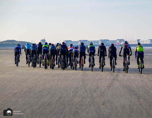 laura op de rug gezien met open armen in een duinpan