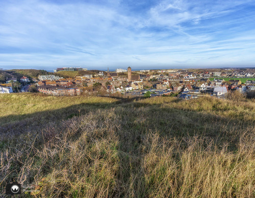 laura op de rug gezien met open armen in een duinpan