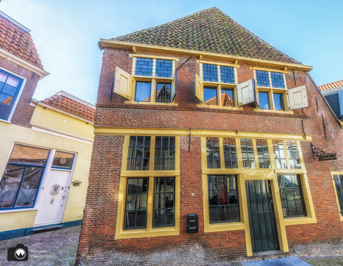 Oud huis met gele kozijnen en luiken