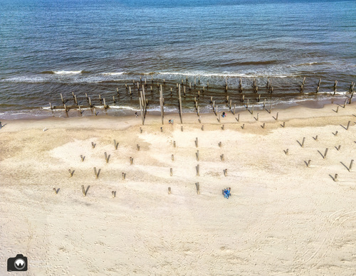 een breed strand met strandpalen en laura en adriaan ertussen