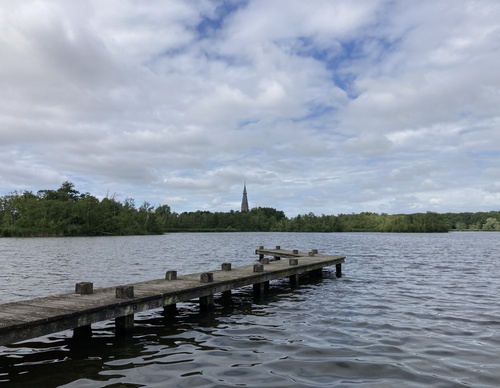 Steiger in het water met in de verte een kerk en bos